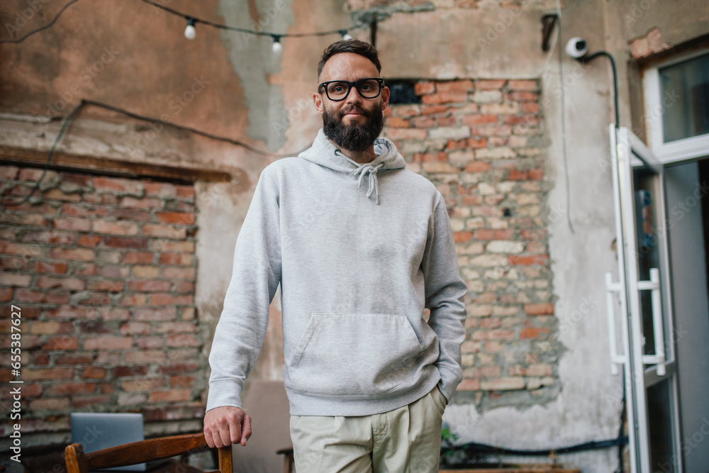 Sticker urban portrait of handsome hipster man with a beard wearing a gray blank hoodie with space for your 