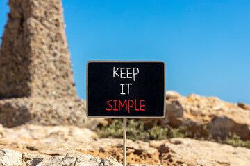 Keep it simple symbol. Concept word Keep it simple on beautiful black chalk blackboard. Beautiful brown stone blue sky background. Business motivational keep it simple concept. Copy space.