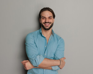 happy young man in denim shirt smiling and crossing arms
