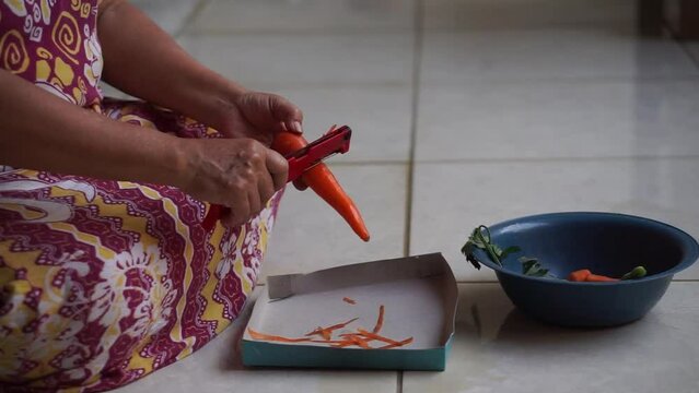 A woman is cutting carrots on a cutting board. The process of preparing food and seasonings.