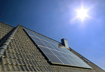 Fototapeta premium Solar panels producing clean energy on a roof of a residential house