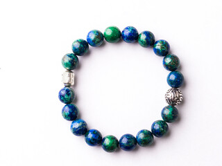 A blue and green beaded bracelet on a white surface
