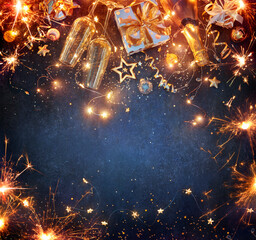 New Year Celebration - Lights With Champagne Glasses And Gift Boxes With Golden Ornaments On Blue...