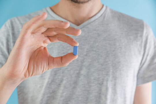 Man holding a PrEP blue pill. HIV prevention using Pre-Exposure Prophylaxis medicine. Men health. AIDS prevention concept