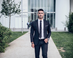 A man in a suit and tie walking down a sidewalk