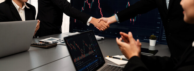 Stock investors celebrate successful profit from selling stock and shaking hand with each other,...