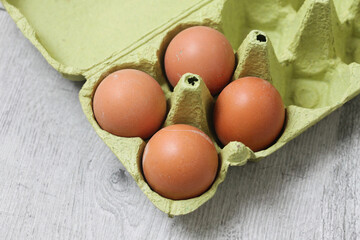 Chicken eggs in cardboard box. Eggs isolated on wood. Healthy countryside farm food production...
