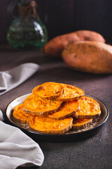 Pieces of sweet baked potatoes on a plate on the table vertical view