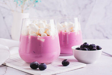 Cocktail with blueberry yogurt and marshmallows in a glass on the table
