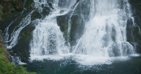 Fototapeta premium Mountain landscape with powerful waterfall in green coniferous forest. Full-flowing stream in Alps. Gollinger Wasserfall in Austria.