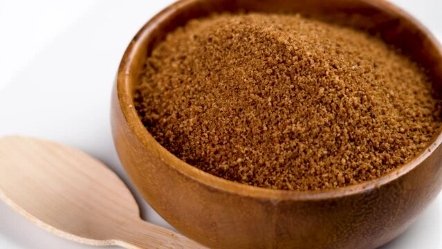 Coconut sugar made from the kithul palm (Caryota urens) in wooden bowl with bamboo teaspoon. Rotation