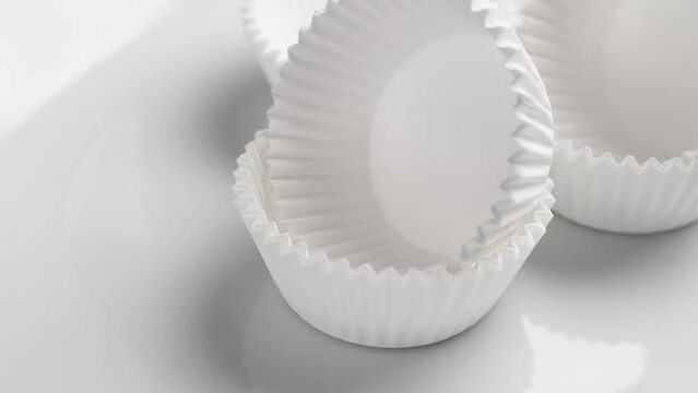 Empty unfilled paper muffin cupcake molds close up on a white. Rotation