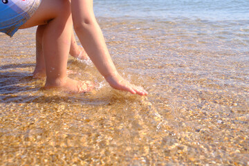 A small child soaked his palms in the sea