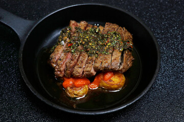 spanish chimichurri beef steaks with potato and spicy brava sauce in black background