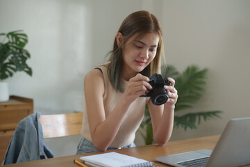 Creative designer woman checking photo in camera and work graphic design on laptop in home studio