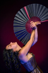 artistic portrait in studio Hispanic woman posing with head back raising fans