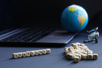 Esperanto inscription next to a globe, an open laptop and glasses. Concept of using the artificial...