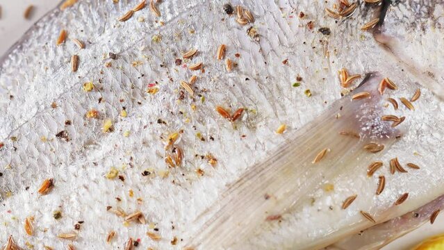 Raw dorado fish sprinkled with black pepper and cumin, close-up. Boom shot