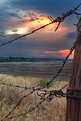 Barbed wire fence old west sunset