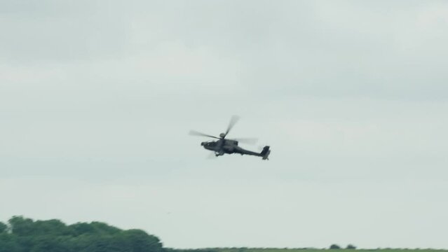 British army AH-64E Boeing Apache Attack helicopter gunship AH64E slows to left banked turn and low flight
