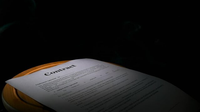 Dismissal contract on black background. A view of dismissal business documents on the table in white fume against black background.