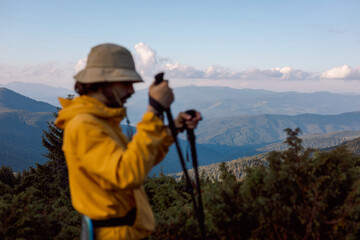 selective focus: portrait of a hiker with trekking poles and backpack climbing or descending mountain hiking trails