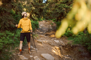 Obraz premium portrait of a hiker with trekking poles and backpack climbing or descending mountain hiking trails