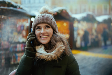smiling woman at winter fair in city talking on phone
