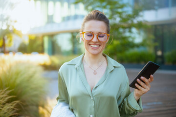 female employee in green blouse and eyeglasses using smartphone