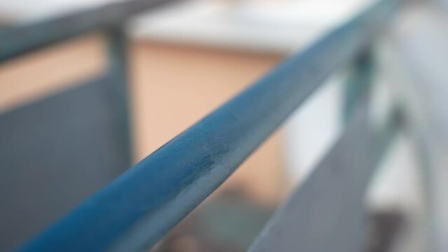 Close-up shot of renovated balcony frame painted with protective blue colour, repairman in gloves using paintbrush for coating metal surface with special chemical blue colour to prevent corrosion