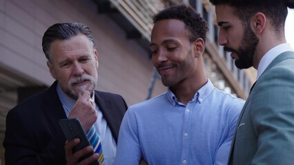 African American entrepreneur shows ideas on phone to business colleagues. Successful office coworker proudly look at new online marketing campaign on mobile. Professional people outside company.