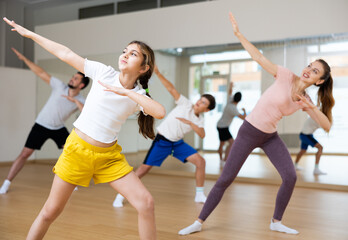 Fototapeta na wymiar Girl dancing modern dance with family during group rehearsal in gym.
