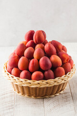 Ripe juicy apricots in a wicker basket on a white background. Harvesting.