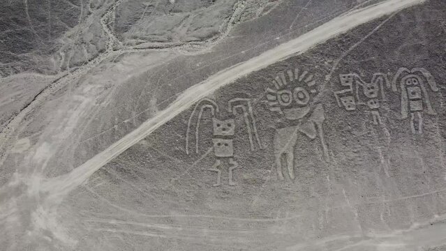 Camera moving over group of human figures of the Nazca Lines geoglyphs made in the soil of the Nazca Desert Aerial video