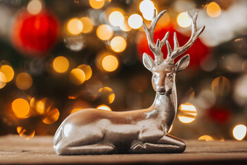 Christmas deer on red and gold blurred bokeh background. Christmas decorations.silver deer figurine...