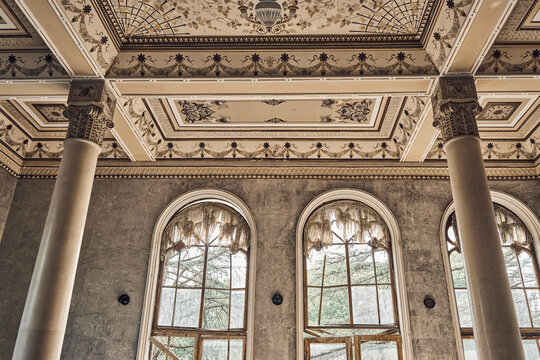  Abandoned soviet spa resort (sanatorium) Shakhter (Miner), in Tskaltubo, Georgia. Luxurious ancient hall with columns, painted ceiling, arched windows. Stalin Empire style - Powered by Adobe
