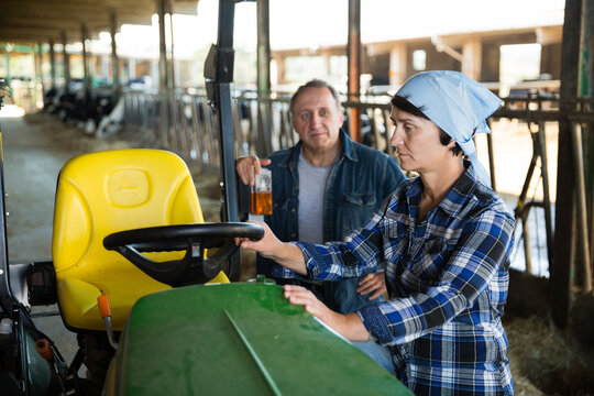 Dairy farm workers standing near tractor, communicating during break in work