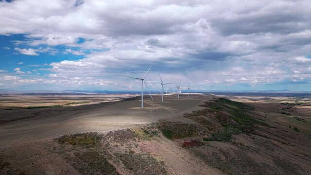 Spinning wind turbines n the desert steppe against blue skies.