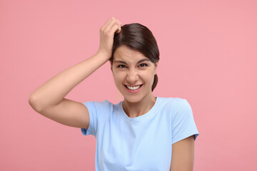 Portrait of embarrassed young woman on pink background