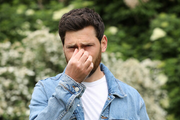Man suffering from seasonal spring allergy outdoors