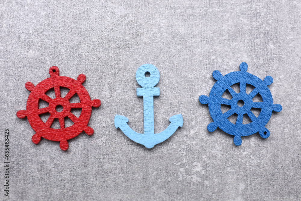 Poster Anchor and ship wheel figures on light grey table, flat lay