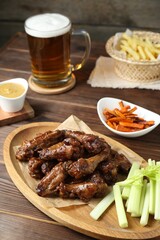 Delicious chicken wings served with beer on wooden table