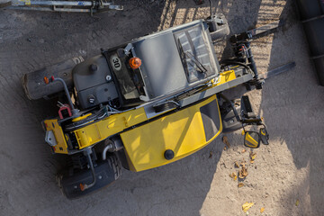 Details of a generic yellow tractor loader working on Construction site. Above view