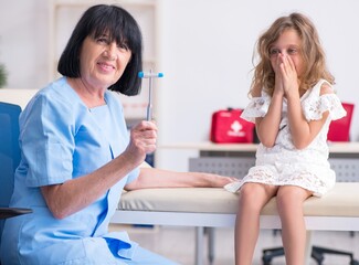 Little girl visiting old female doctor