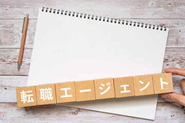転職エージェントと書かれたブロック、ノート、ペン、手