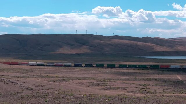 Train hauling wagons through the desert steppe under a brilliant blue sky.