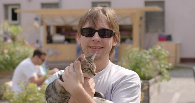 Portrait of young man holding cat against backdrop of urban environment. Unique bond between humans and pets, moments of genuine connection and solace. deep connection shares with four-legged friend.