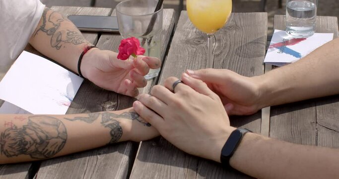 Nonverbal communication. Close-up shot of couple hands on a date. Young woman hands are adorned with tattoos. Tattoos on her hands can be a form of self-expression, artistry, or personal symbolism.