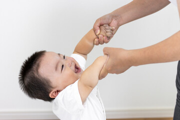 母親と手をつないでつかまり立ちする赤ちゃん（男の子、生後9カ月、1歳、日本人）