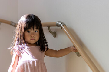 階段の手すりを握る女の子（3歳、日本人）